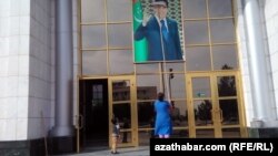 Tam süpüriji prezident Gurbanguly Berdimuhamedowyň portretini düşektaýak bilen ýuwýar. (arhiw suraty)