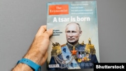 Bir adam &#253;&#252;z&#252;nde Russi&#253;anyň prezidenti Wladimir Putiniň suraty go&#253;lan The Economist žurnalyny tutup dur. Onuň &#253;azgysy &#171;Patyşa doguldy&#187;. &#160;Fransi&#253;a. Strasburg. 2017-nji &#253;ylyň 28-nji okt&#253;abry.