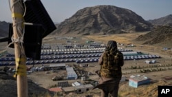 د طالبانو یو حکومتي سرتېری په تورخم کې د یوې غونډۍ له سره له پاکستانه د ایستل شویو افغانانو لنډمهالي کیمپ ته ګوري - د مې ۳۱مې انځور.