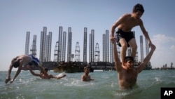 A beach on the Caspian Sea in Baku, Azerbaijan, with oil platforms in the background. 