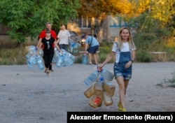 Жінка йде з порожніми бутлями, окупований Донецьк, 21 серпня 2025 року