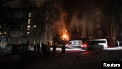 Жители се събират край жилищна сграда, докато електроцентрала гори след атака на руски безпилотен самолет в Киев на 19 декември