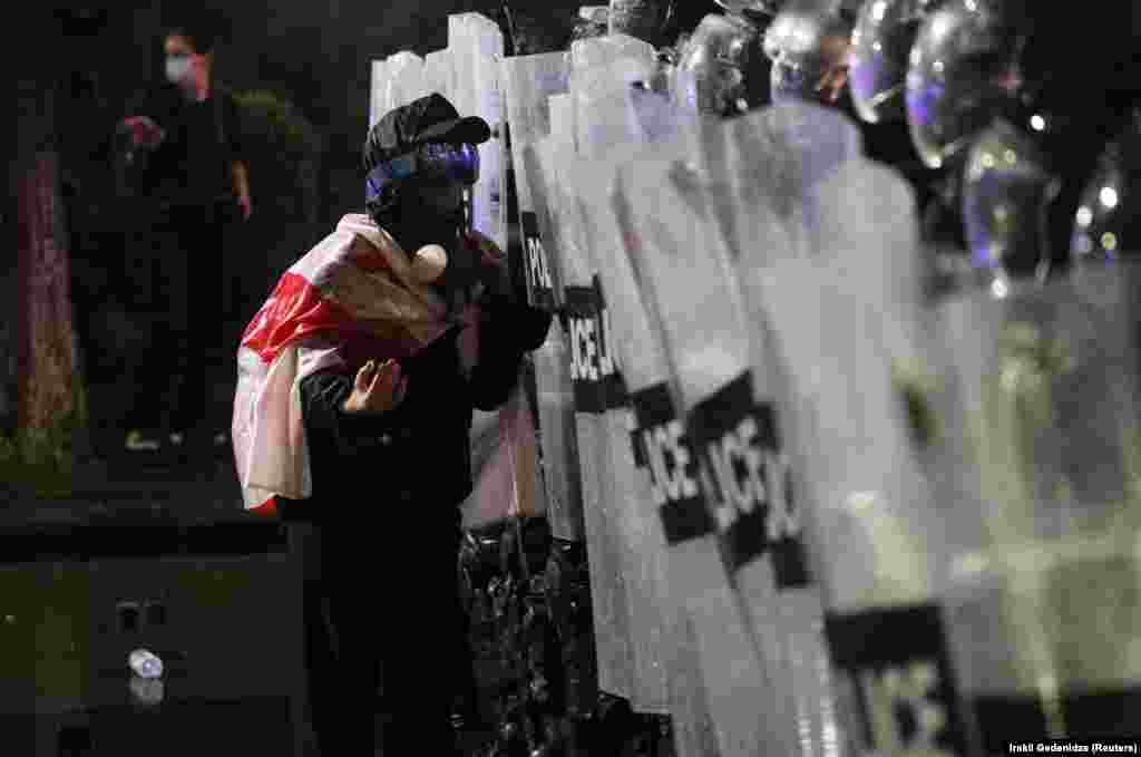 Учасник мітингу, що сховав обличчя та огорнувся прапором, підійшов впритул до поліцейських