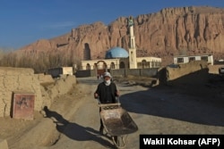 A Hazara man pushes a wheelbarrow along a road in Bamiyan Province.