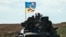 UKRAINE – A Ukrainian tank rides with a flag picturing Ukraine and US flags shaking hands in Novostepanivka, Kharkiv region, on September 19, 2022