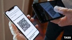 Un vizitator prezintă codul QR pe telefonul său mobil, la intrarea în restaurantul „Mama Budet Rada” din Moscova, care acceptă doar accesul persoanelor vaccinate anti-covid