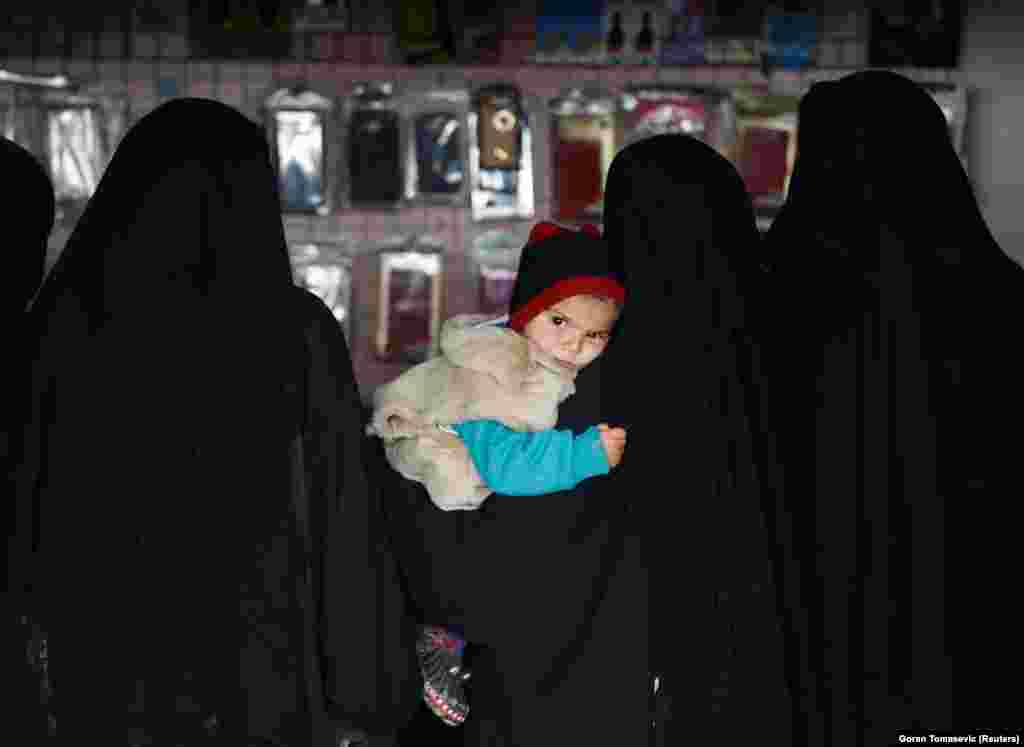 A child is held by a woman inside a shop inside the al-Hol camp.