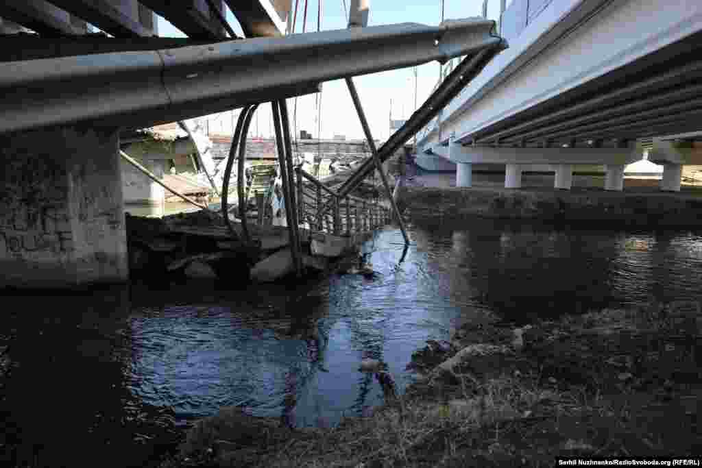 Кінуты дзіцячы вазок празь пераход каля разбуранага Раманаўскага мосту.Зьлева фота 11 сакавіка 2022 году, справа — з сакавіка 2025 году