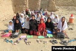 Profesoara Mahajera Armani, alături de clasa ei de fete, pozează în zona de studiu, fondată de Comitetul de Dezvoltare Rurală din Bangladesh (BRAC), în afara orașului Jalalabad, Afganistan, 19 septembrie 2015.