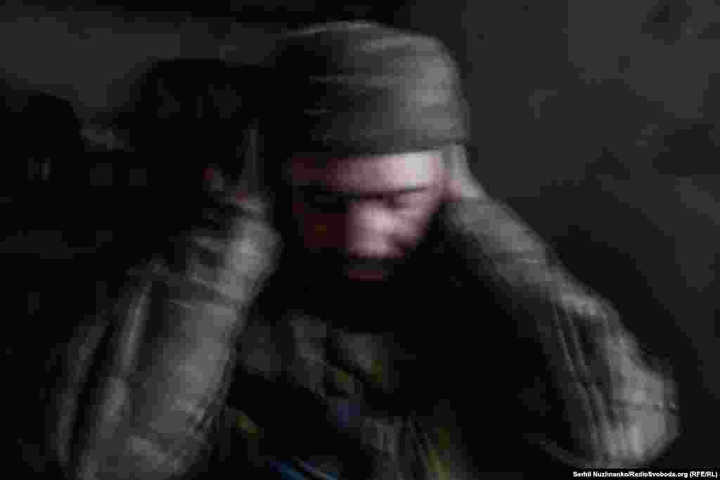 Український військовий у Часовому Яру молиться, закривши вуха, під час обстрілу російською армією позицій ЗСУ в травні 2023 року