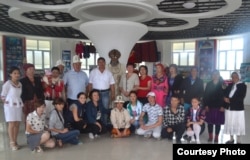 Кыргызстандык саякатчы илимпоздор жана студенттер кытайлык кыргыздардын тобу менен КЭРдин Кызыл-Суу Кыргыз автоном облусуна караштуу Ак-Чий ооданындагы Кара-Булак айылындагы Жусуп Мамайдын музейинде маркум манасчынын момдон жасалган айкелинин жанында. 30-июль, 2015-жыл.