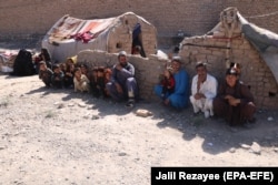An internally displaced Afghan family outside a temporary shelter as they wait for relief from the authorities on the outskirts of Herat on June 15.