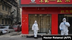 آرشیف، کارمند صحی چین در نزدیک مرد مسن که در نزدیک یک شفاخانه در شهر ووهان وفات کرده است.