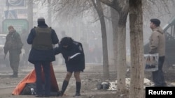 Полиция осматривает тело погибшего в результате обстрела жилого квартала в Мариуполе