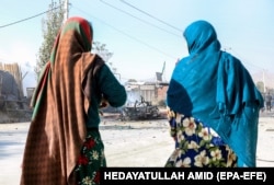 Două femei afgane stau lângă locul unei explozii din Kabul, Afganistan, 27 octombrie 2020. Cel puțin trei persoane au fost ucise și alte doisprezece rănite în explozia unei mașini capcană.